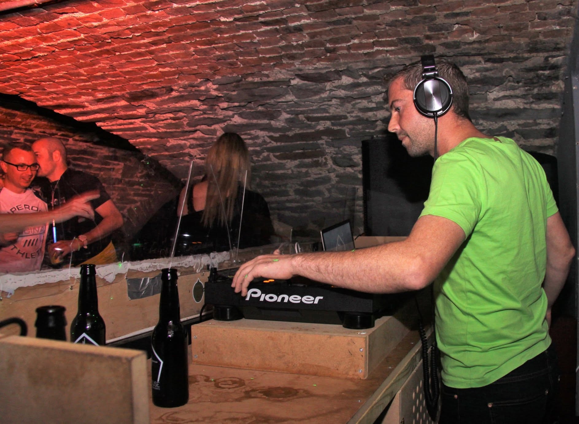 DJ on Pioneer decks under red brick arches
